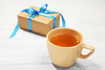 Cup of tea and gift box on wooden background
