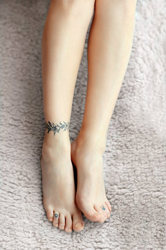 Female feet with tattoo on carpet