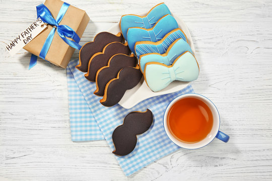 Happy Father's Day concept. Tasty cookies and cup of tea on wooden background