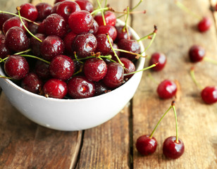 Bowl with fresh ripe cherries on wooden background