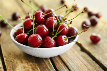 Bowl with fresh ripe cherries on wooden background