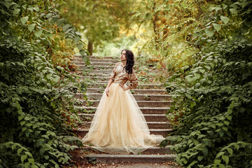 Beautiful girl in a luxurious dress walks in autumn park. The princess is on the old stairs in gold dress.Fashionable toning.creative colors © kharchenkoirina