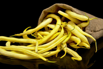 Stack of yellow beans in linen sack on black