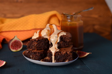 Brownie with walnuts, salted caramel, figs on a dark blue background with a yellow cloth