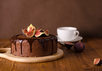 Chocolate cake with figs, chocolate cream and chocolate icing on brown wooden background. Milchmaedchen.