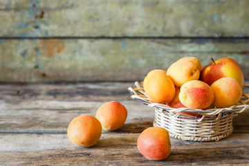Ripe apricots in white bowl on wooden background