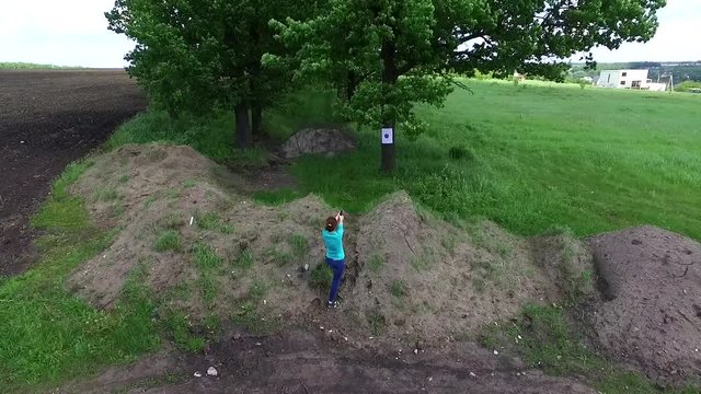 girl practicing shooting at targets in countryside, aerial video