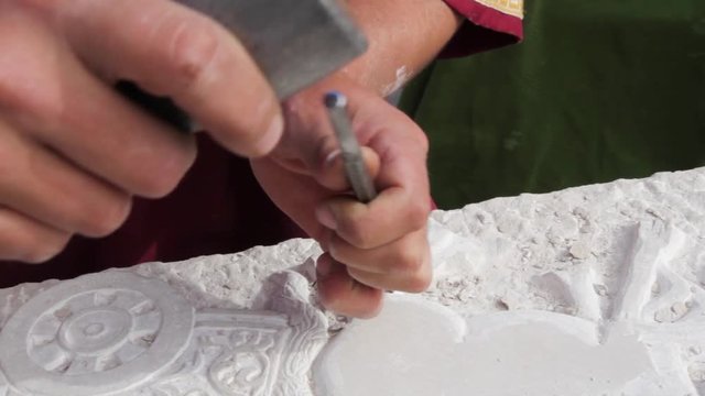 Mano tallando en piedra  con cincel y maza
