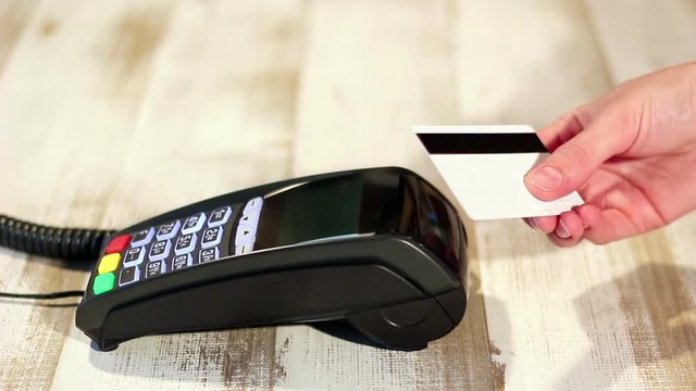 Swipe credit card over pos terminal. Making contactless NFC payment.