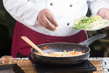 Chef putting bean sprouts and leek to the pan