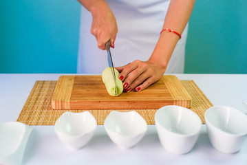 Close up picture of young lady's hands cutting cucumber