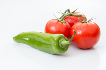 Three tomatoes and a chili pepper on white