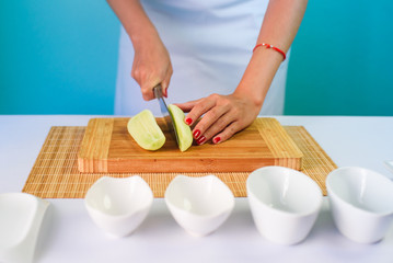 Close up picture of young lady's hands cutting cucumber