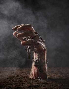 Hand of dead with chain climbs out of the ground