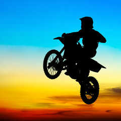 Obraz na płótnie Canvas silhouette of motocross rider jump in the sky at sunset