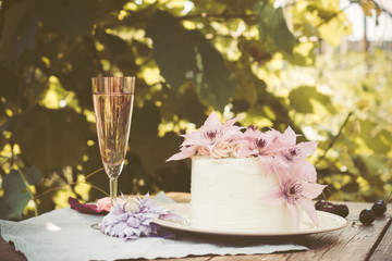 Creamy cake with clematis flowers on the wooden table. Shallow depth of field. Toned image.