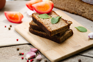 Rye bread. Bread on a wooden table, tomatoes and garlic