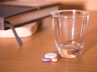 pills in a cup of glass with notebook blur for background