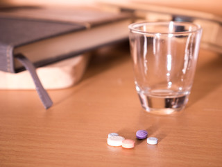 pills in a cup of glass with notebook blur for background