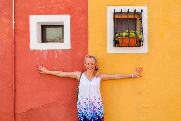 Woman traveler on the background of one of the many colored painted buildings of Burano Island, near Venice, Italy