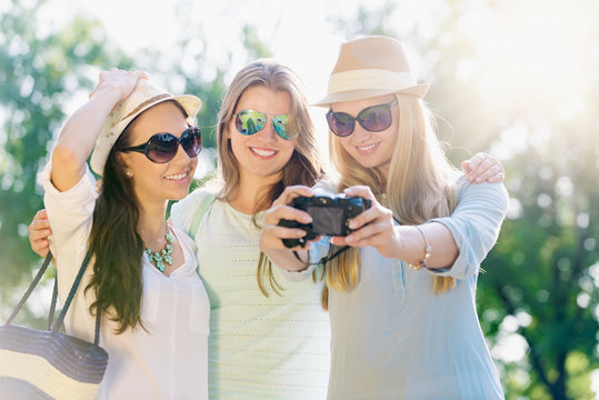 Friends taking picture at summer holidays, girls with camera taking self-portrait on their travel vacation