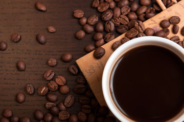 Cup of coffee and coffee beans on dark brown table