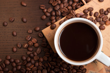 Cup of coffee and coffee beans on dark brown table