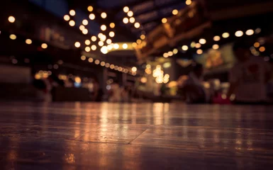 Foto op Plexiglas Restaurant Leeg houten tafelblad op vervagen café-restaurant in donkere achtergrond