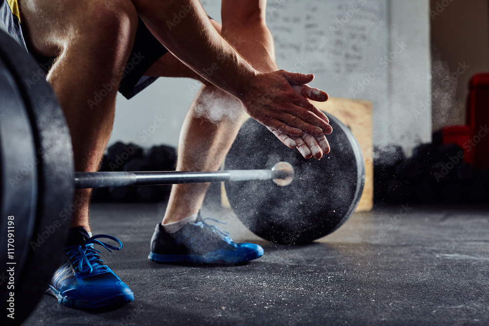 Wall mural Closeup of weightlifter clapping hands before  barbell workout a