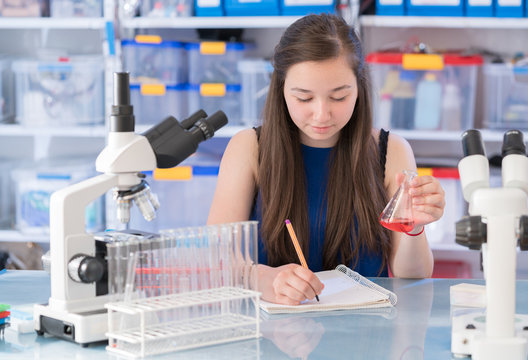 Teen schoolgirl in chemical klassroom with test tubes