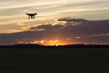 Drone silhouetted against orange sunset