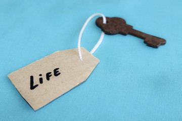 The concept of a happy life - the old key with a tag on turquoise background.