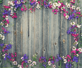 Small field flowers on vintage weathered wooden background. Retro
