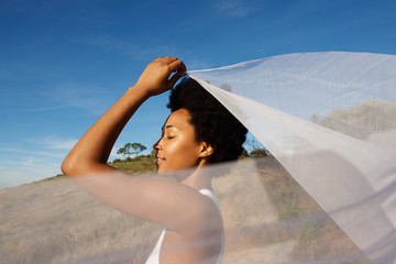 Sensual young woman holding a scarf in air