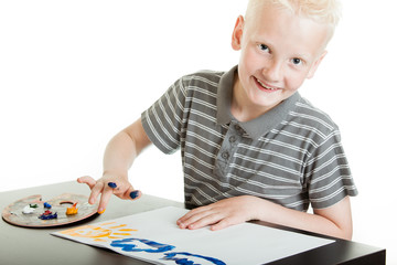 Friendly little boy doing finger painting