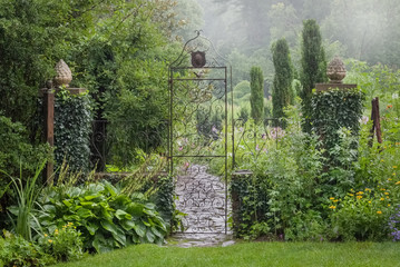 Obrazy  Brama ogrodowa i kamienna ścieżka w deszczowe letnie popołudnie