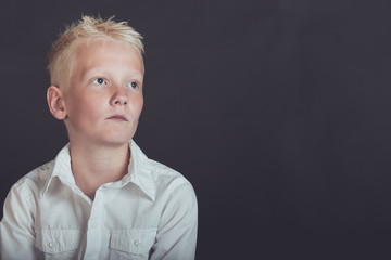 Pensive young boy looking upward over black