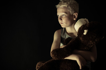 Introvert little boy in dim light holding toy