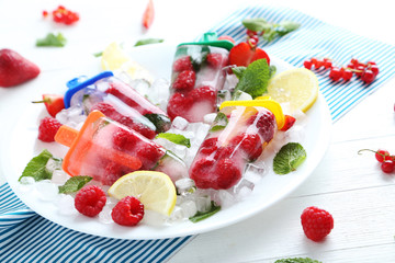 Popsicles with berries on white wooden table