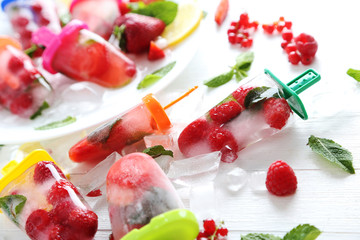 Popsicles with berries on white wooden table