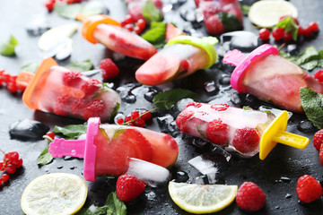 Popsicles with berries on black wooden table