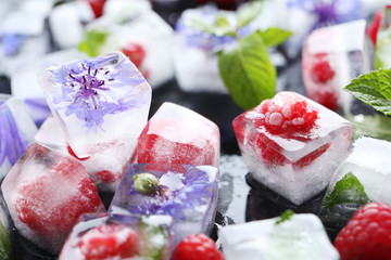Ice cubes with raspberries and mint leaf on wooden table