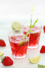 Fresh strawberry drink in glass with lime on wooden table