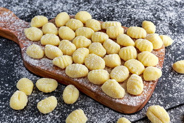 Uncooked homemade gnocchi on wooden cutting floured board 