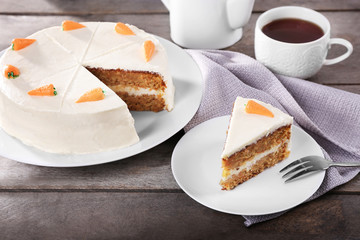 Delicious carrot cake with tea on wooden table