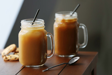 Iced coffee in glass jar with straw on brown wooden table