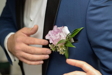 Groom arranging a rose to his boutonniere