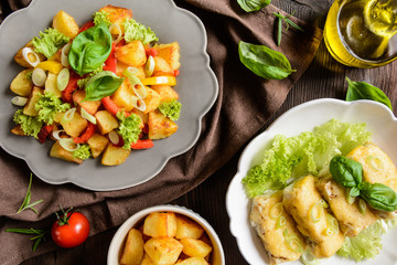 Fried potato salad with lettuce, pepper, onion and baked fish fillets covered with cheese