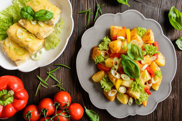 Fried potato salad with lettuce, pepper, onion and baked fish fillets covered with cheese