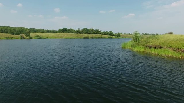 Aerial video of a big lake at countryside. Drone moving forward. 4K Aerial stock footage shot at summer season time.
